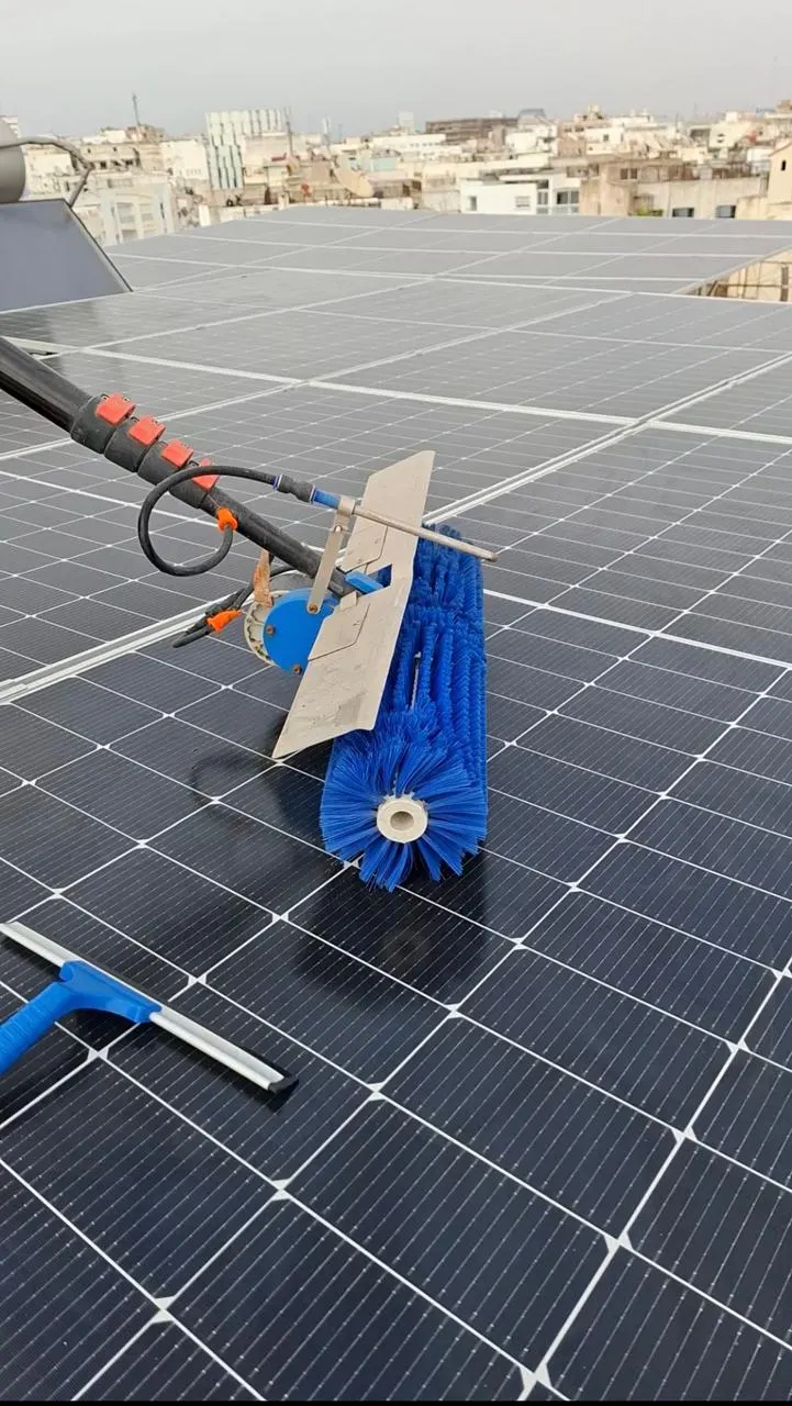 Technicien nettoyant des panneaux solaires avec une brosse rotative sur un toit à Casablanca